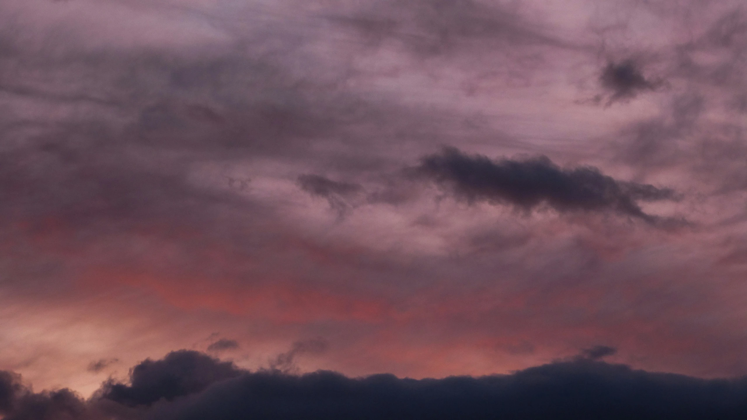 a plane flies under an extremely cloudy sky