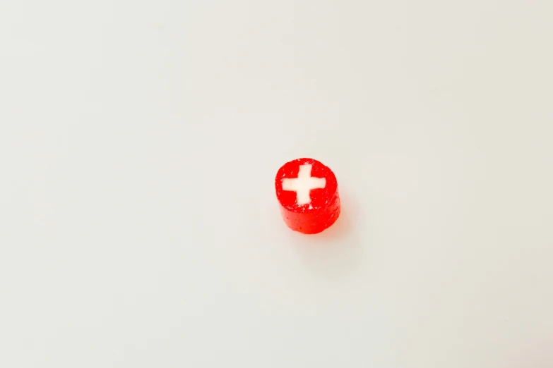 a small red object with a white cross painted on it