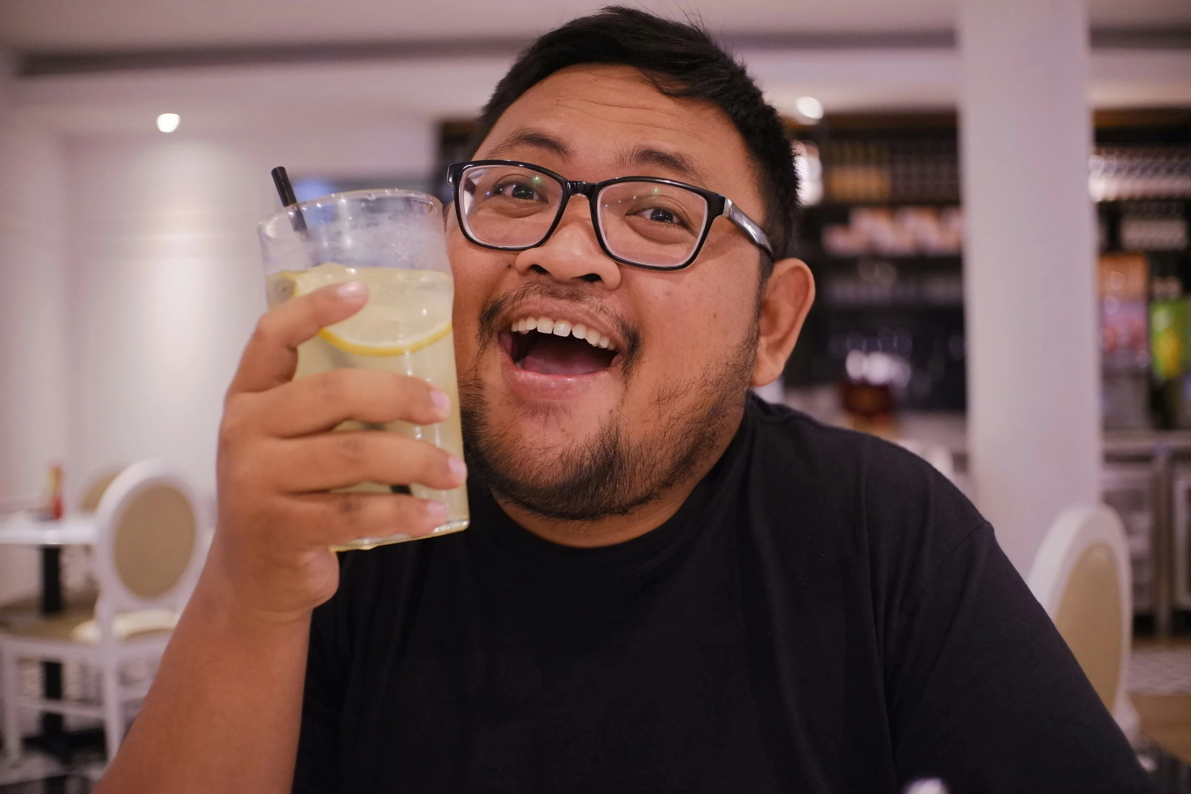 a man wearing glasses and holding a glass with lemon juice in it