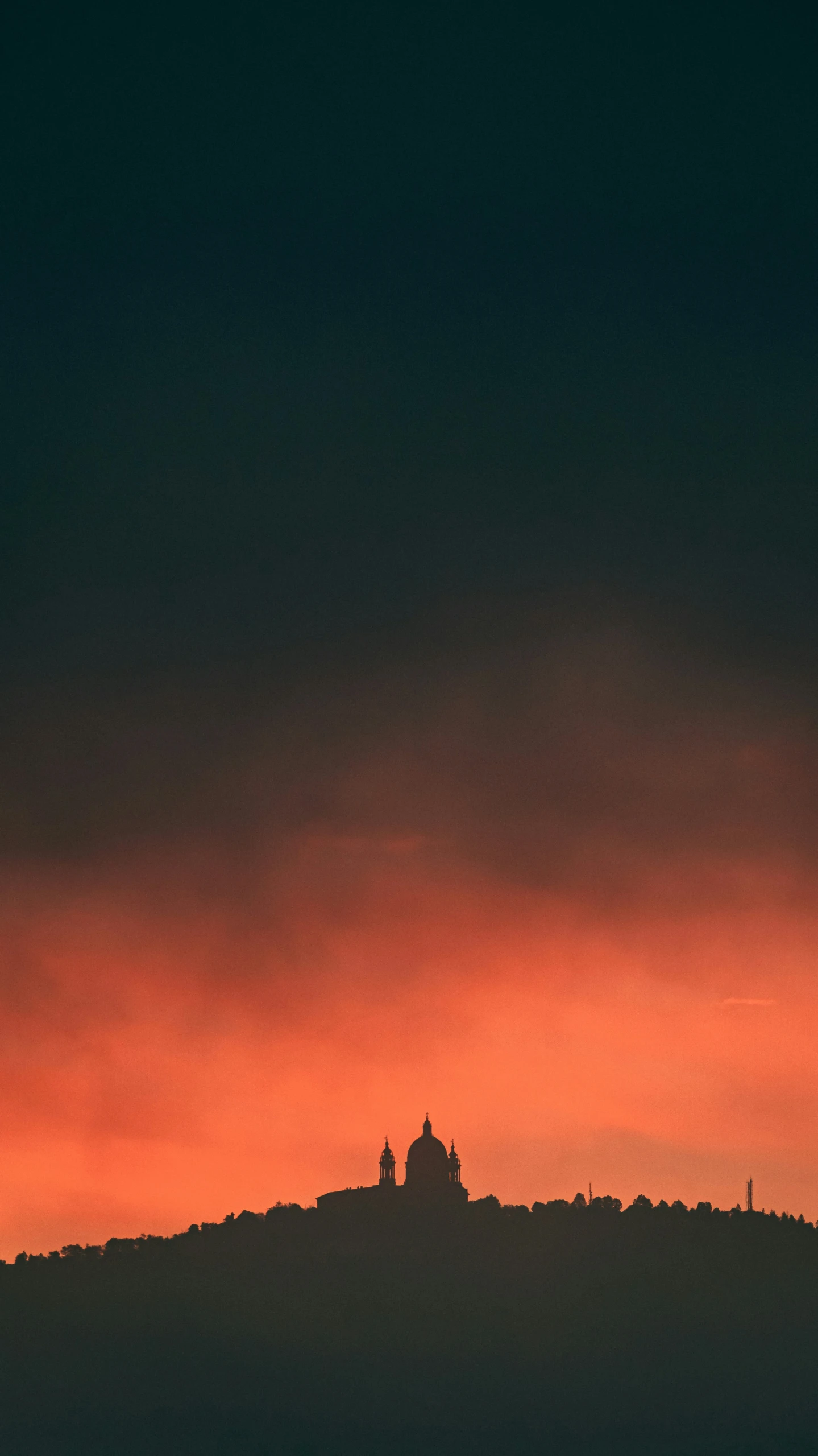 a building atop a hill under a cloudy sky