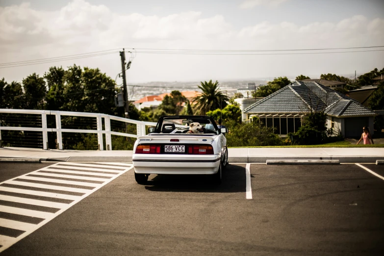 a white sports car with open top parked at the side of an empty street