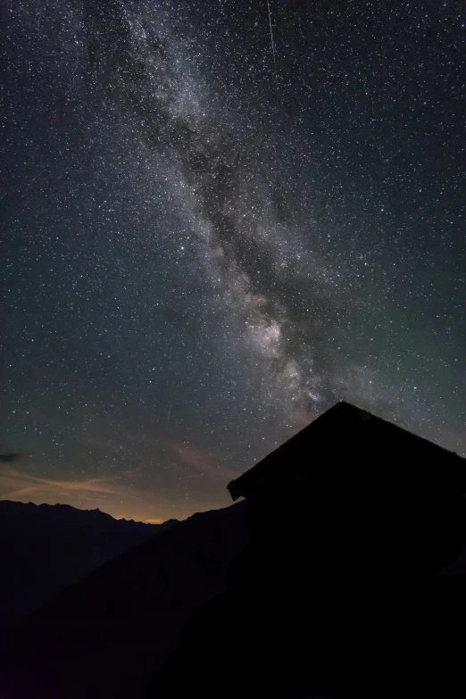 a night sky with stars and a small building