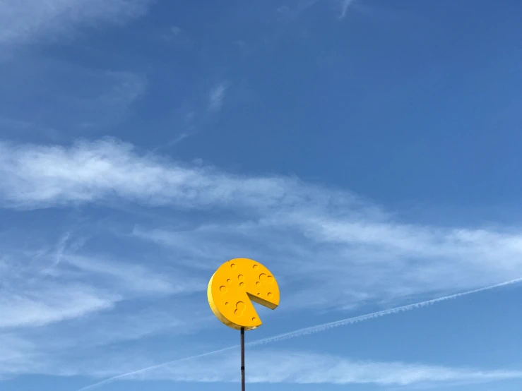 the large yellow sculpture on the metal pole is next to a clear blue sky