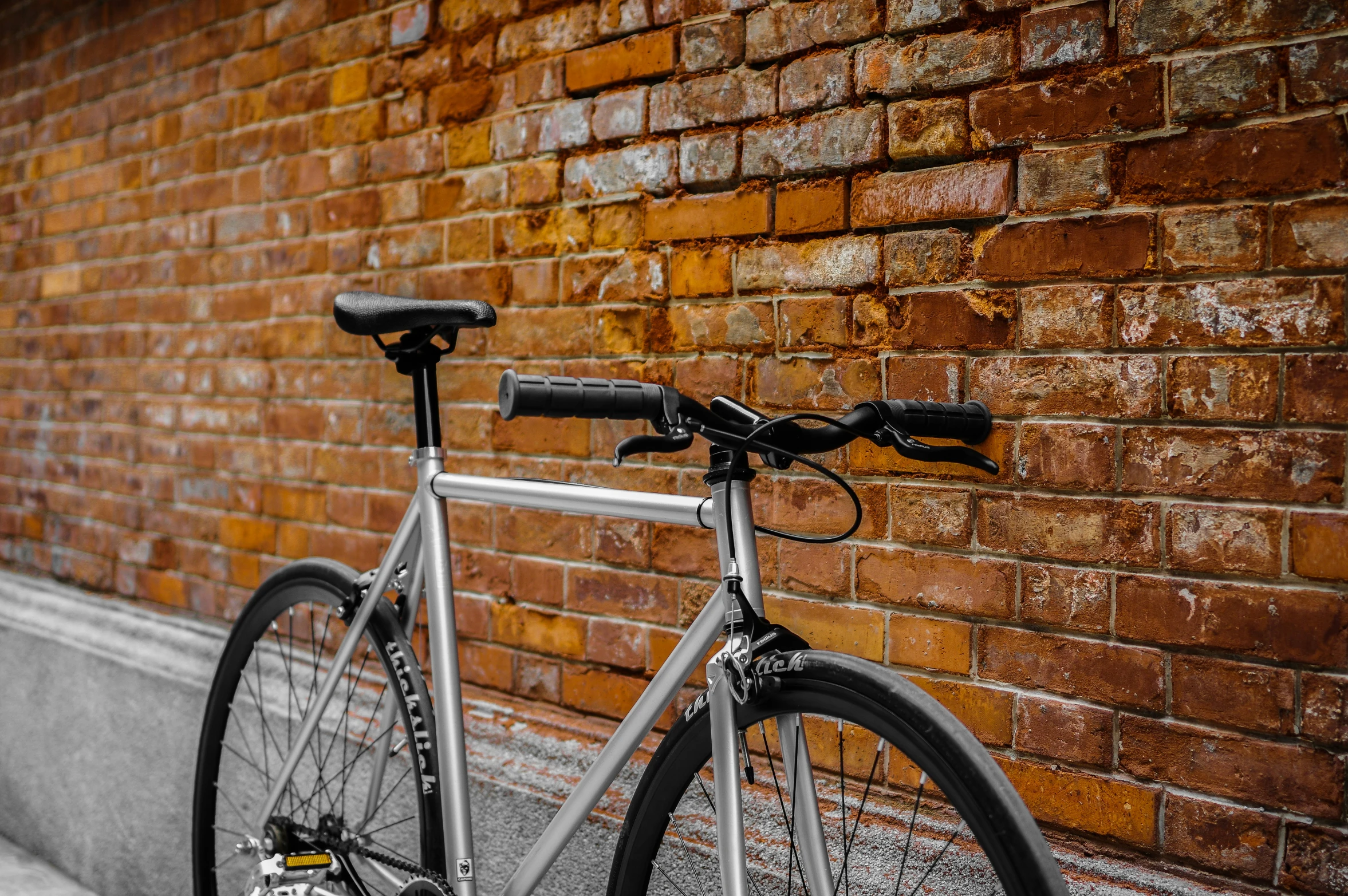 a close up of a parked bicycle near a brick wall