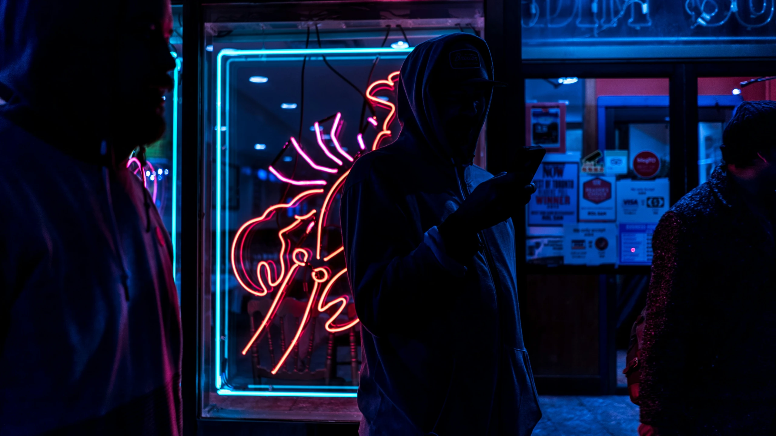 a person in a dark hooded jacket is checking their phone