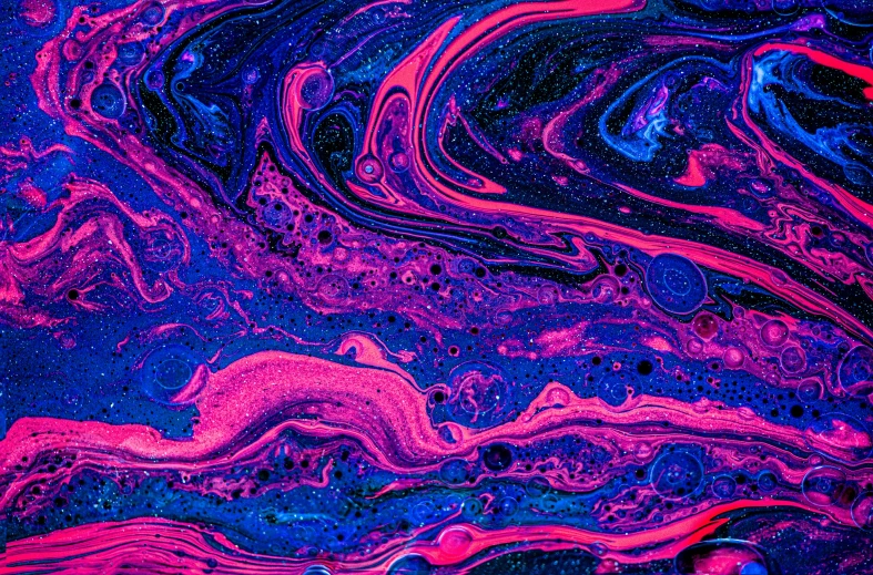 colorful liquid drops in the water that is blue, pink and red