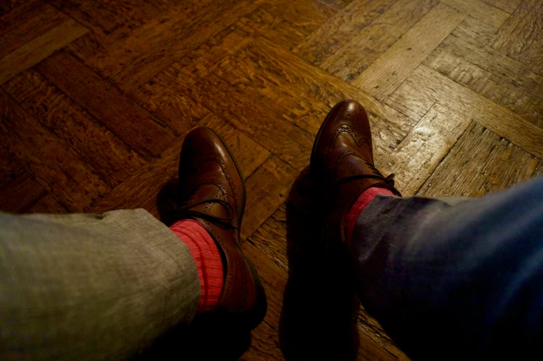 a pair of legs with red socks and brown shoes