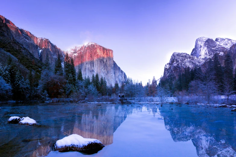 a lake sits with snowy rocks surrounding it