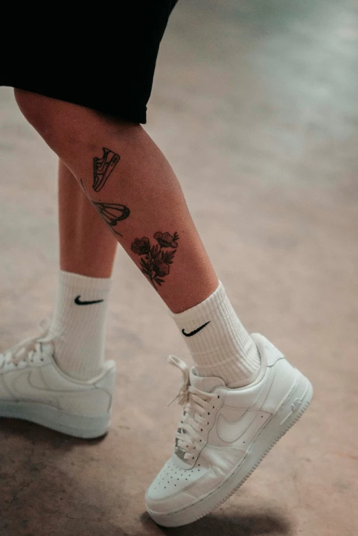 a person with a tattooed leg, and white sneakers