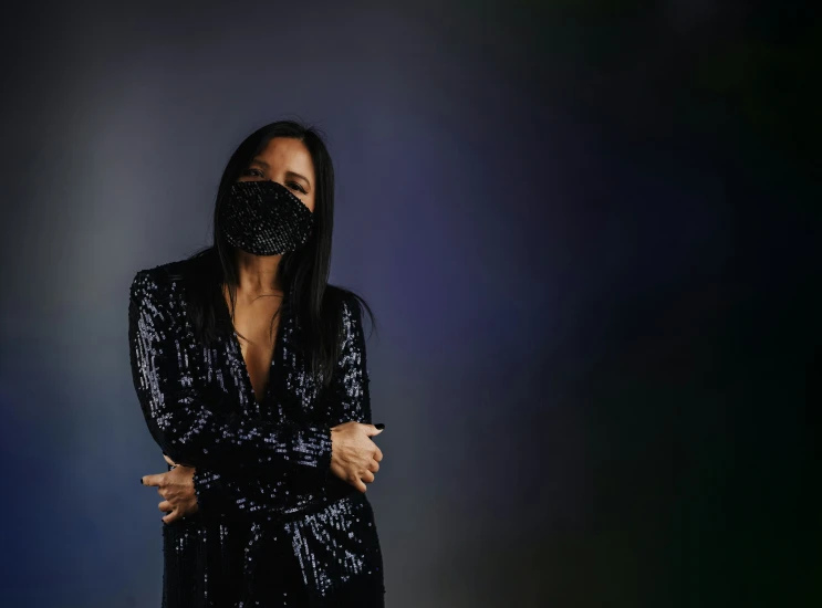 the singer wearing a sequin face mask, pographed against a dark background