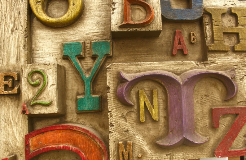 an assortment of colorfully painted wooden letters arranged on wood
