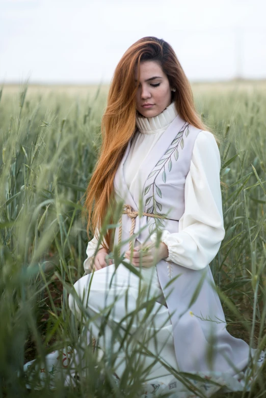 woman sitting down in long grass with her hair up