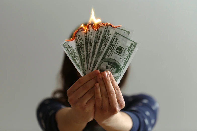 woman holding up five dollar bills and flames