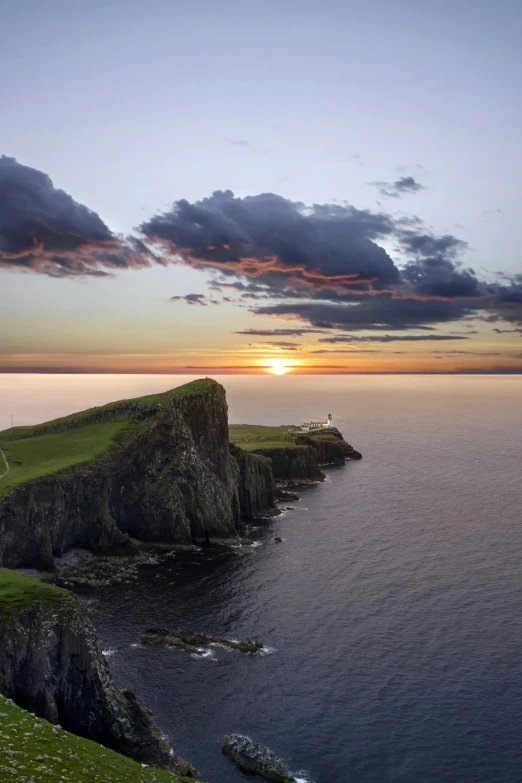 sunset at a remote beach with clouds and a small cliff