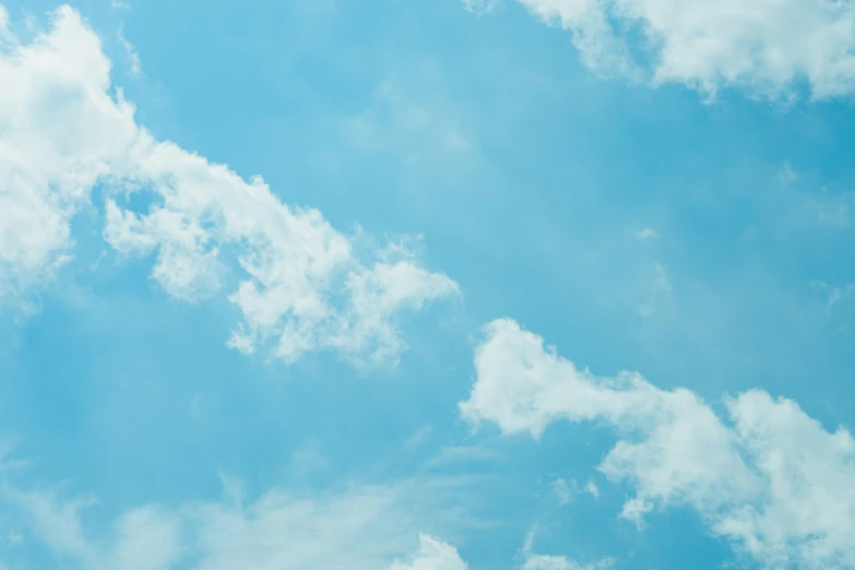 an airplane is flying through the air, with some clouds in the background