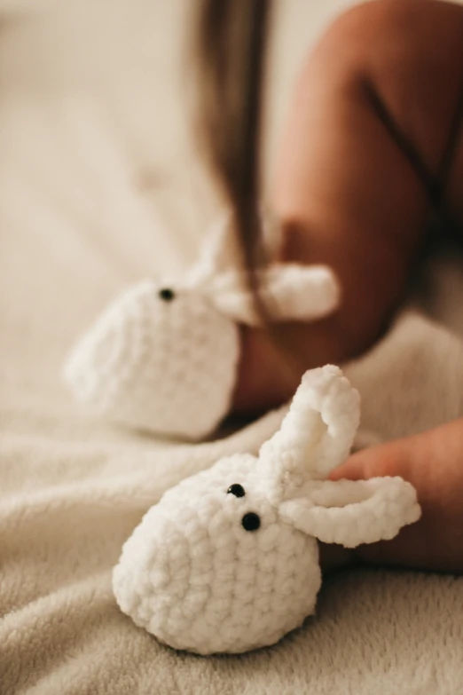 a close up of a person holding two crocheted rabbit decorations