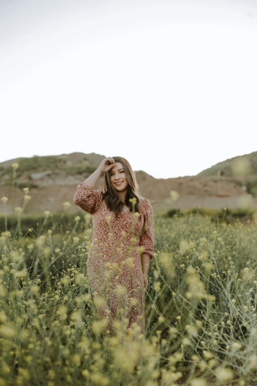 a woman stands in tall grass looking at the sky