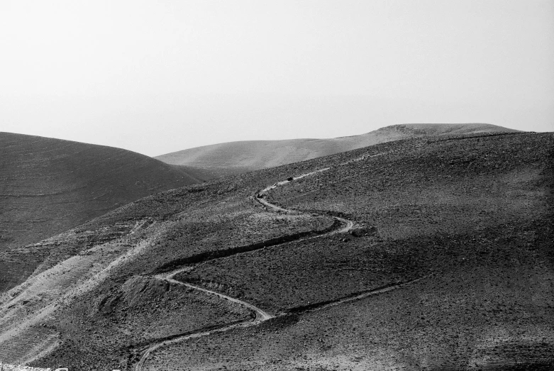 a road curves into the distance in front of hills