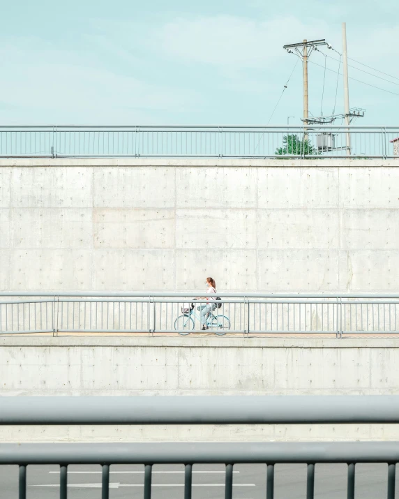 a man is riding a bicycle near a concrete wall