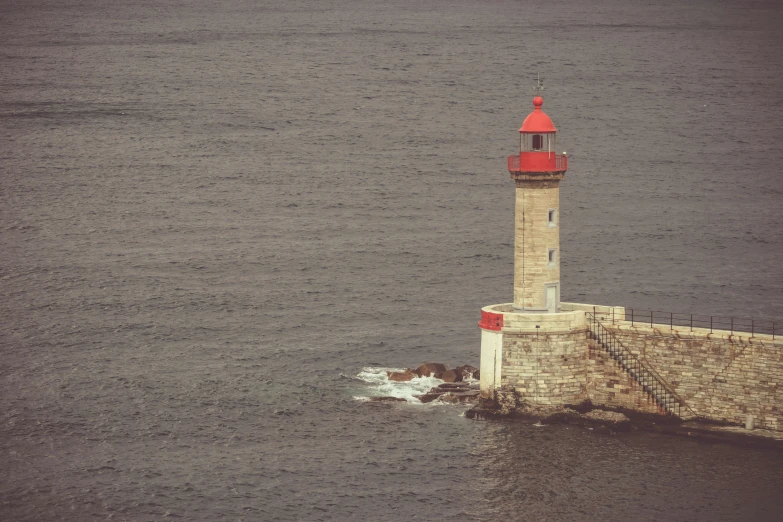 a lighthouse on top of a stone pier in the middle of a body of water