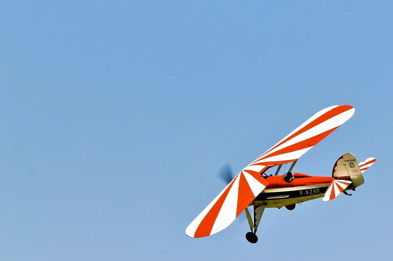 the red and white biplane is flying through the sky