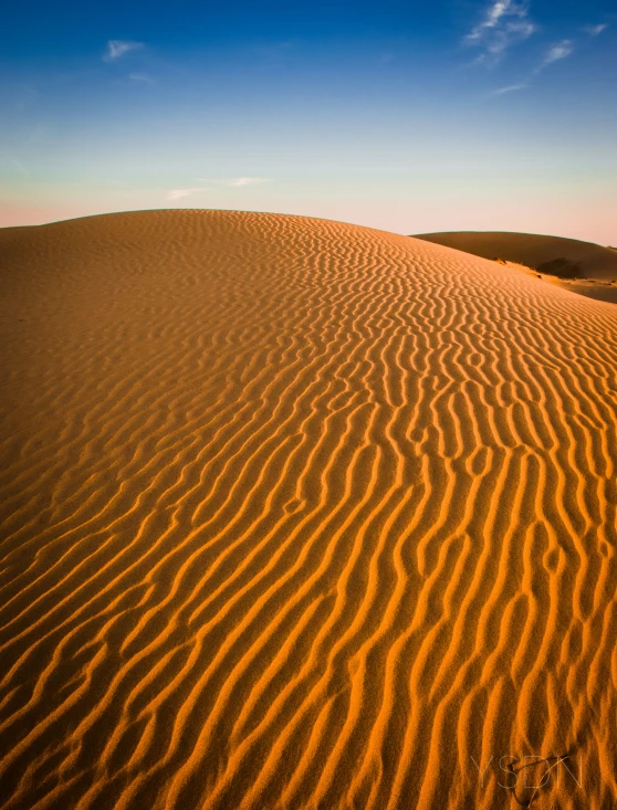 a desert dune at sunset with the sun turning outward