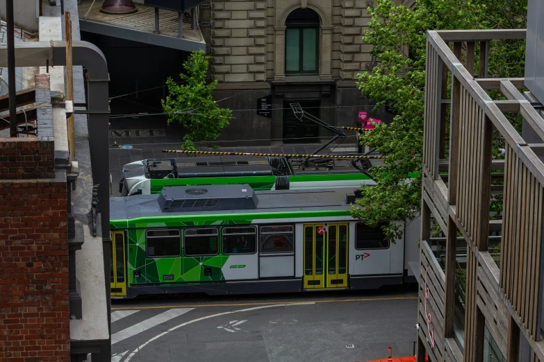 green and white bus on roadway with buildings in background