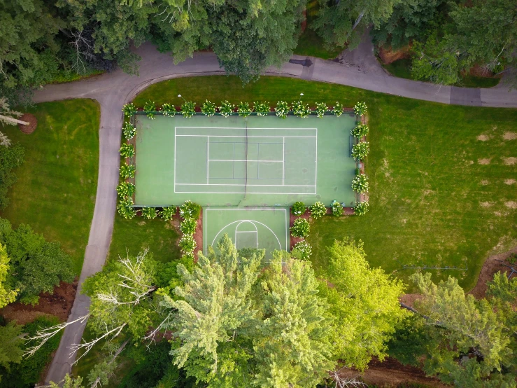 a view from above of an tennis court in the middle of trees