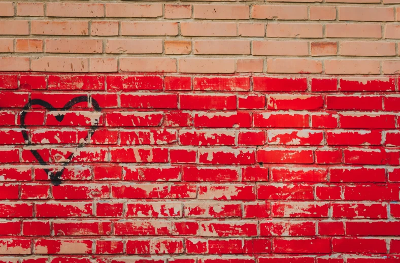 the corner of an old brick wall that has been painted with hearts