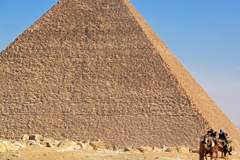 two men riding horses in front of a pyramid