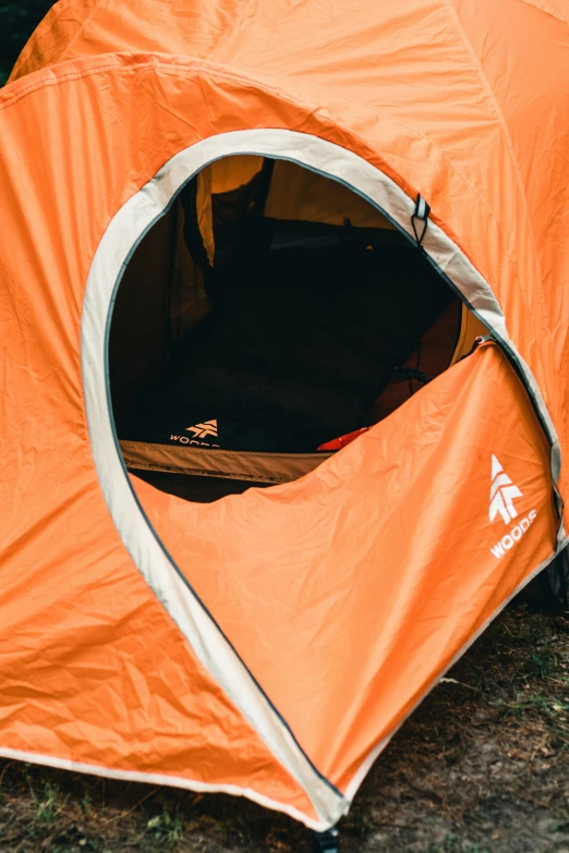 an orange tent on the ground with two legs and three other people inside