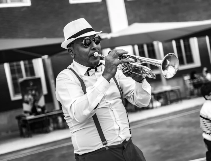 the man is playing his trumpet outside in the street