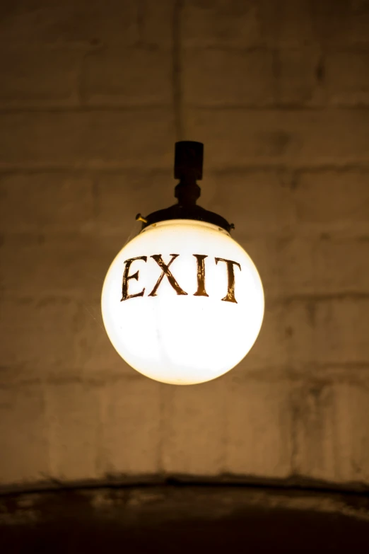 an exit light bulb sitting in front of a brick wall