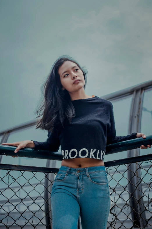 a beautiful woman leaning on a fence while wearing a black shirt