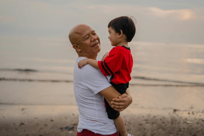 a little boy and man hold an older man on a beach