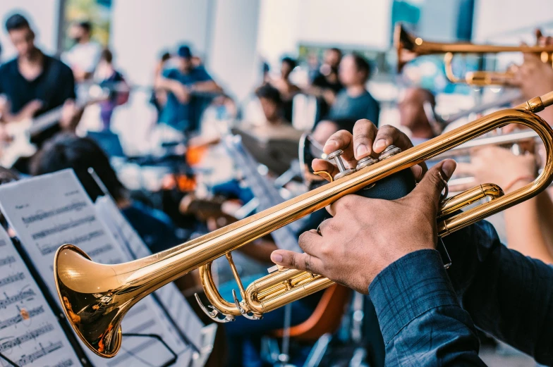 a musician's hand is playing the trumpet while an orchestra plays