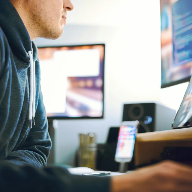 a man sitting in front of a computer and watching tv