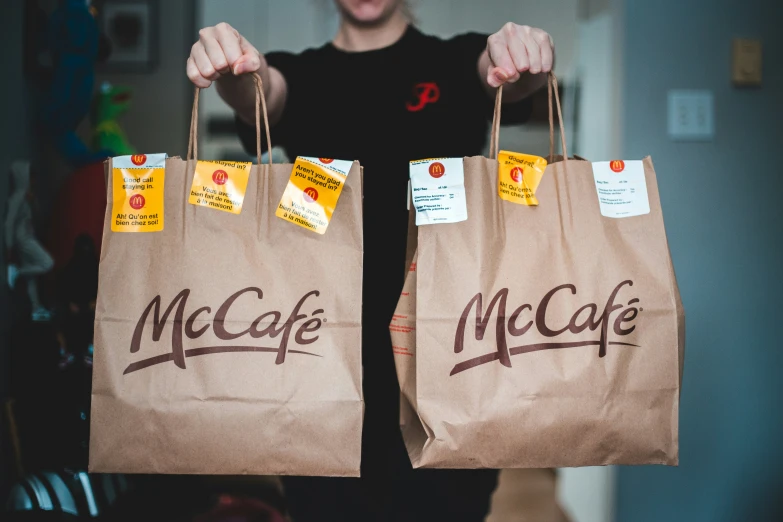 a person holding two bags with packages hanging from them