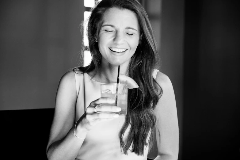 a beautiful woman smiling while holding a glass in her hand