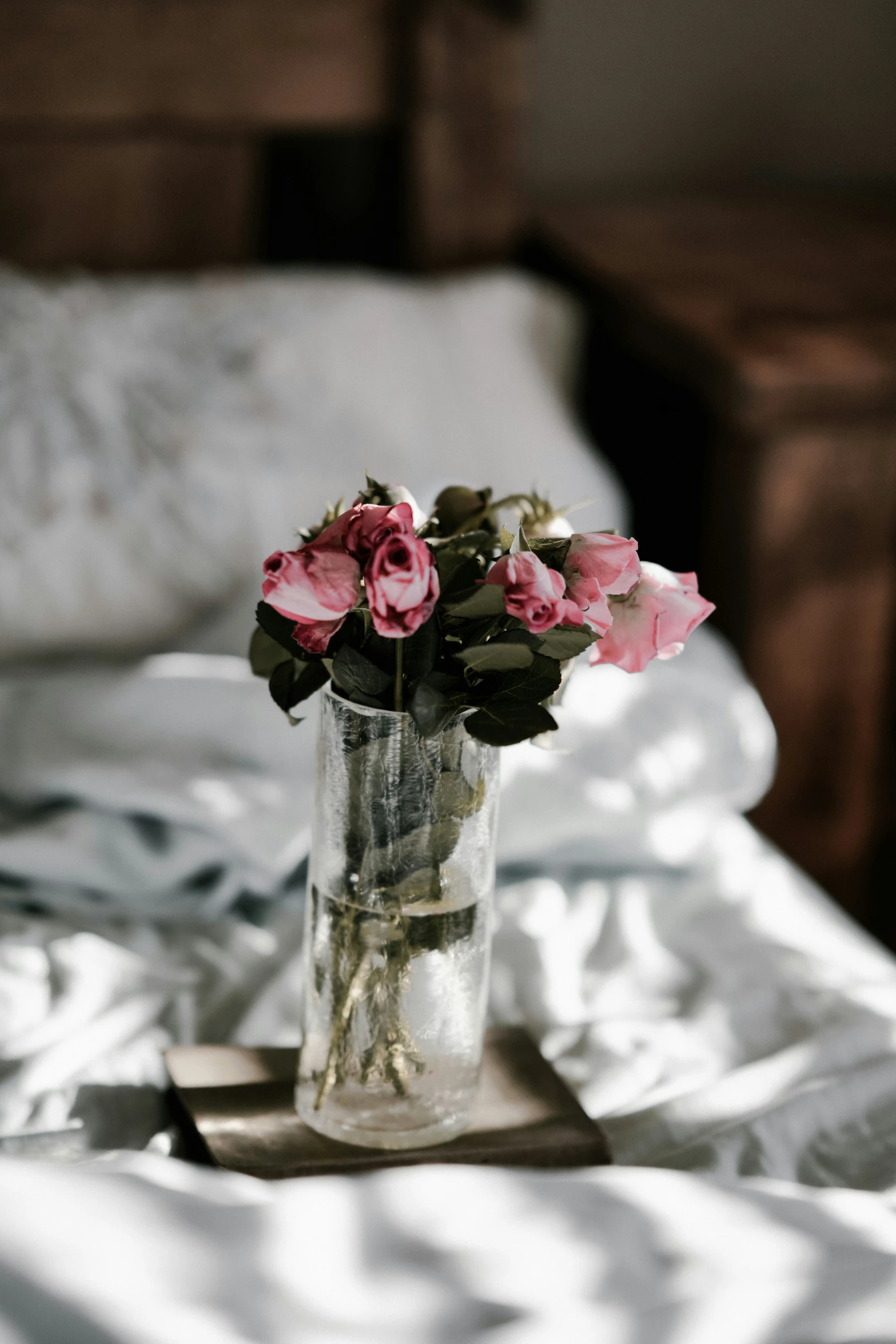 a vase of pink flowers sits on the bed