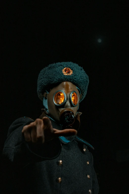 a man wearing a gas mask and a fedora is pointing