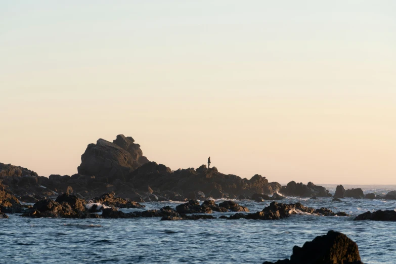 large rocks sitting in the water with people standing on them