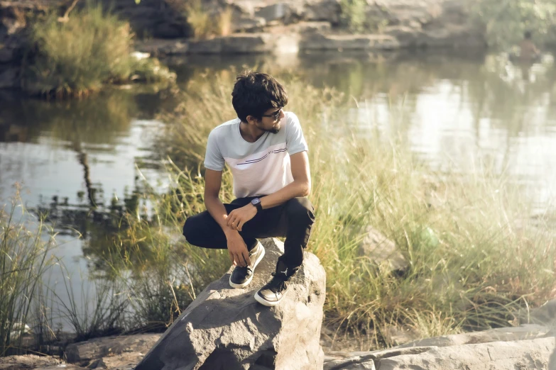 a man on a rock with the water in the background