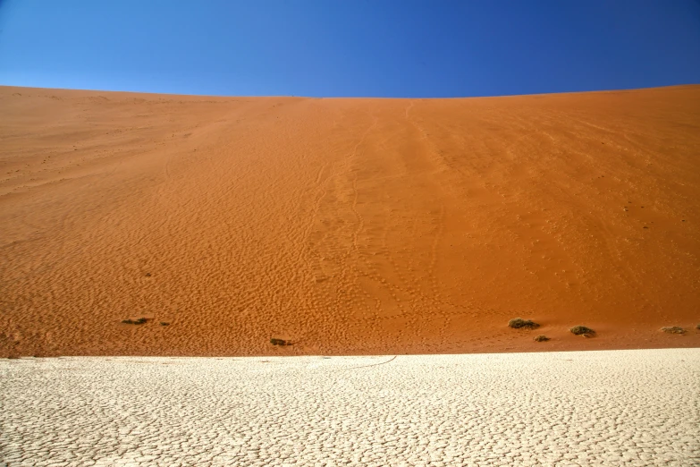 there are footprints on the ground near a large sand dune