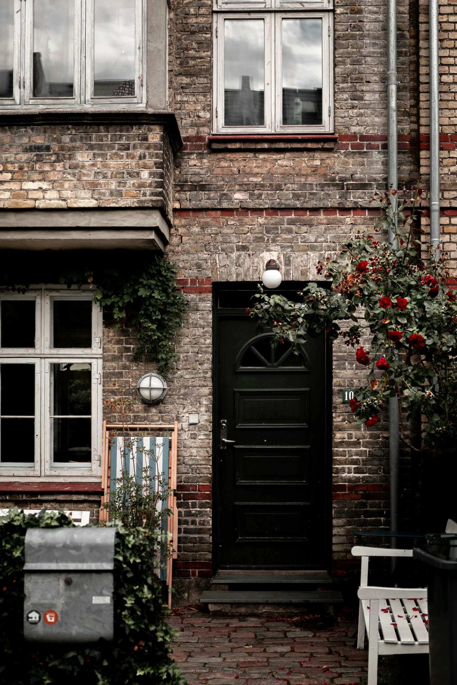 an old house with a bench and potted plants in front