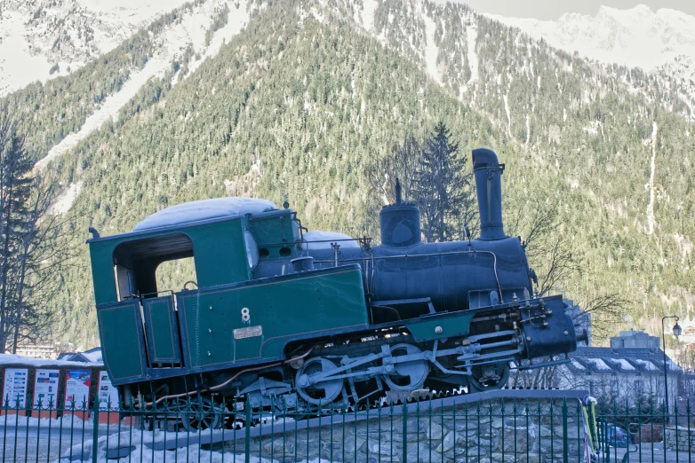 a train that is on the track by some mountains