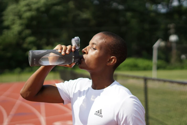 a man drinking from a water bottle outdoors