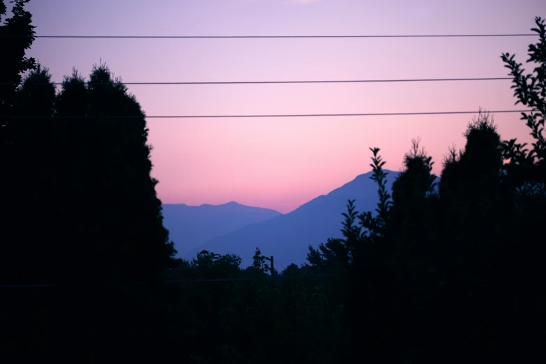 some trees mountains and a line of telephone lines