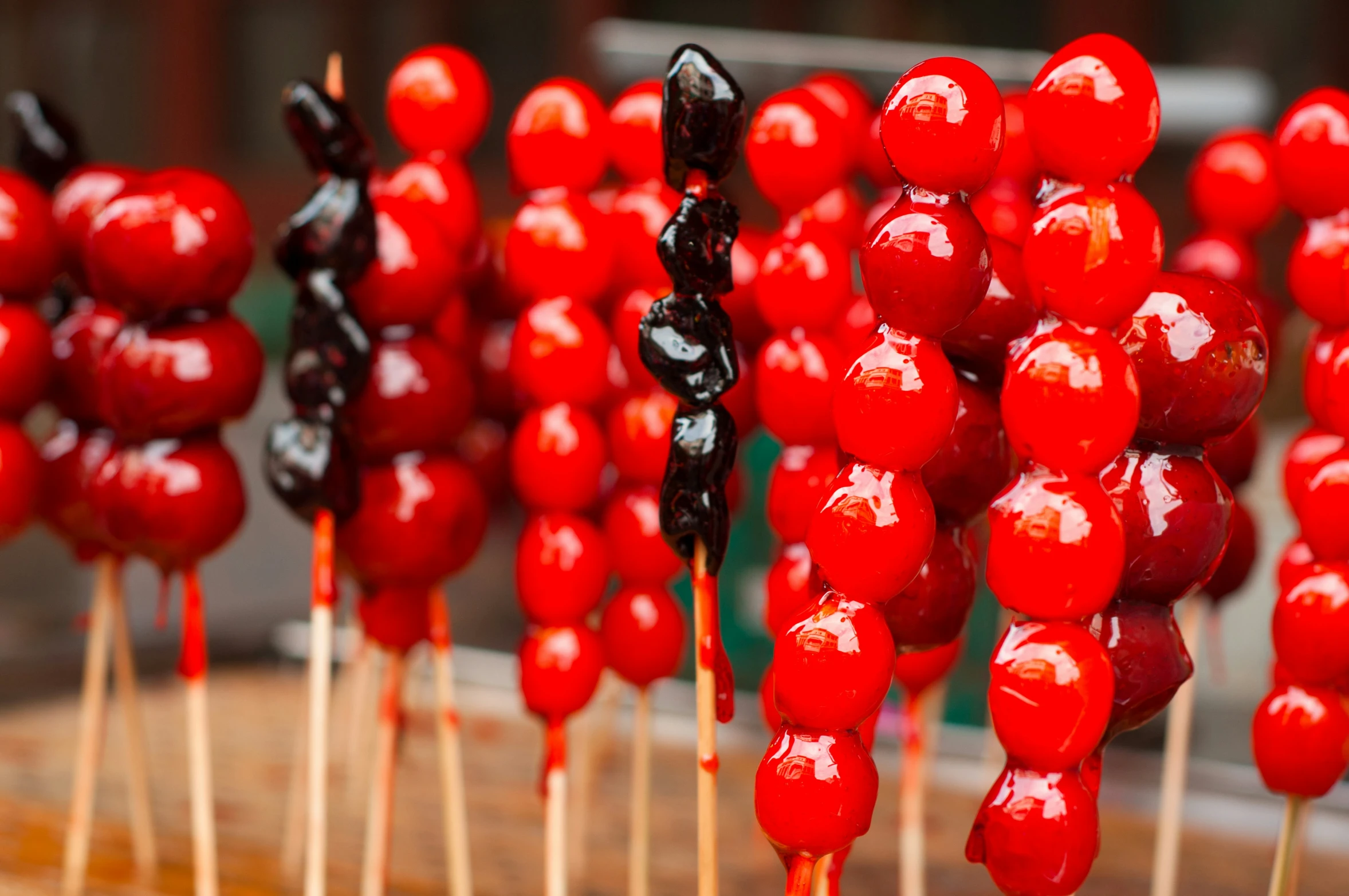 several skewered fruits with long sticks in the foreground