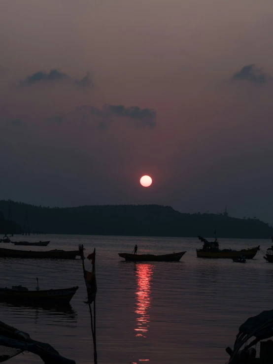 some small boats are in the water with the sun rising